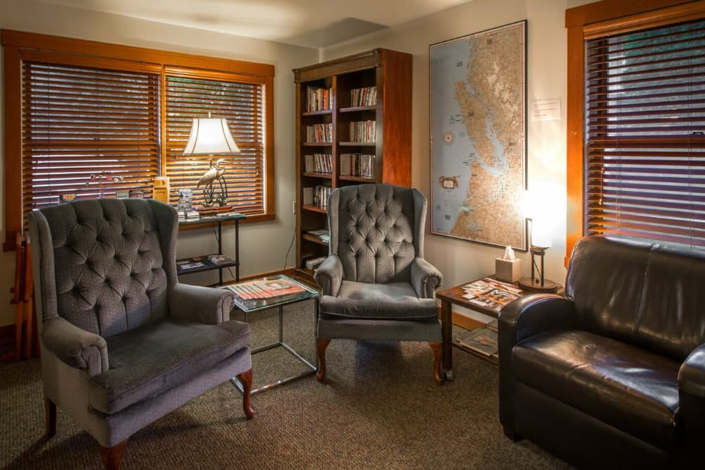 Cozy reading nook featuring two plush armchairs, a coffee table, a bookshelf, and a map on the wall.