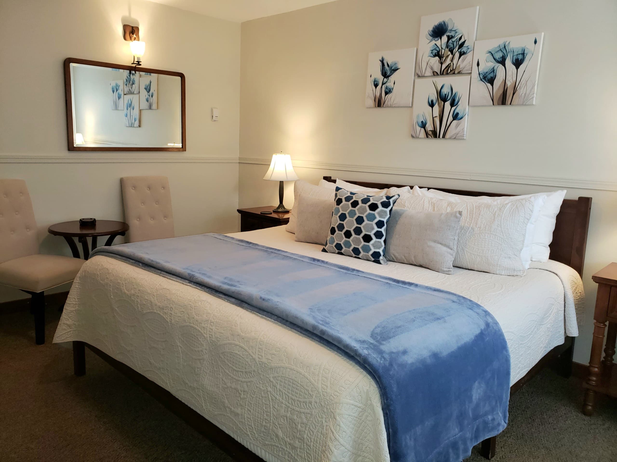 Cozy bedroom featuring a bed with a blue throw, decorative pillows, and floral wall art.