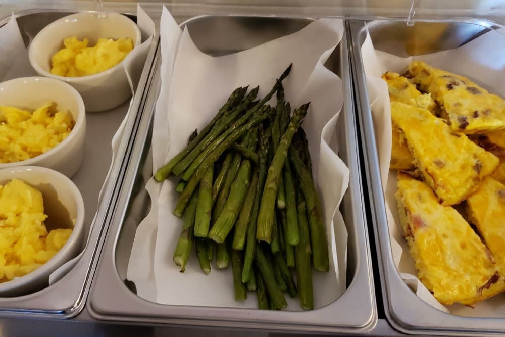 A food display featuring mashed potatoes, asparagus, and egg quiche slices.