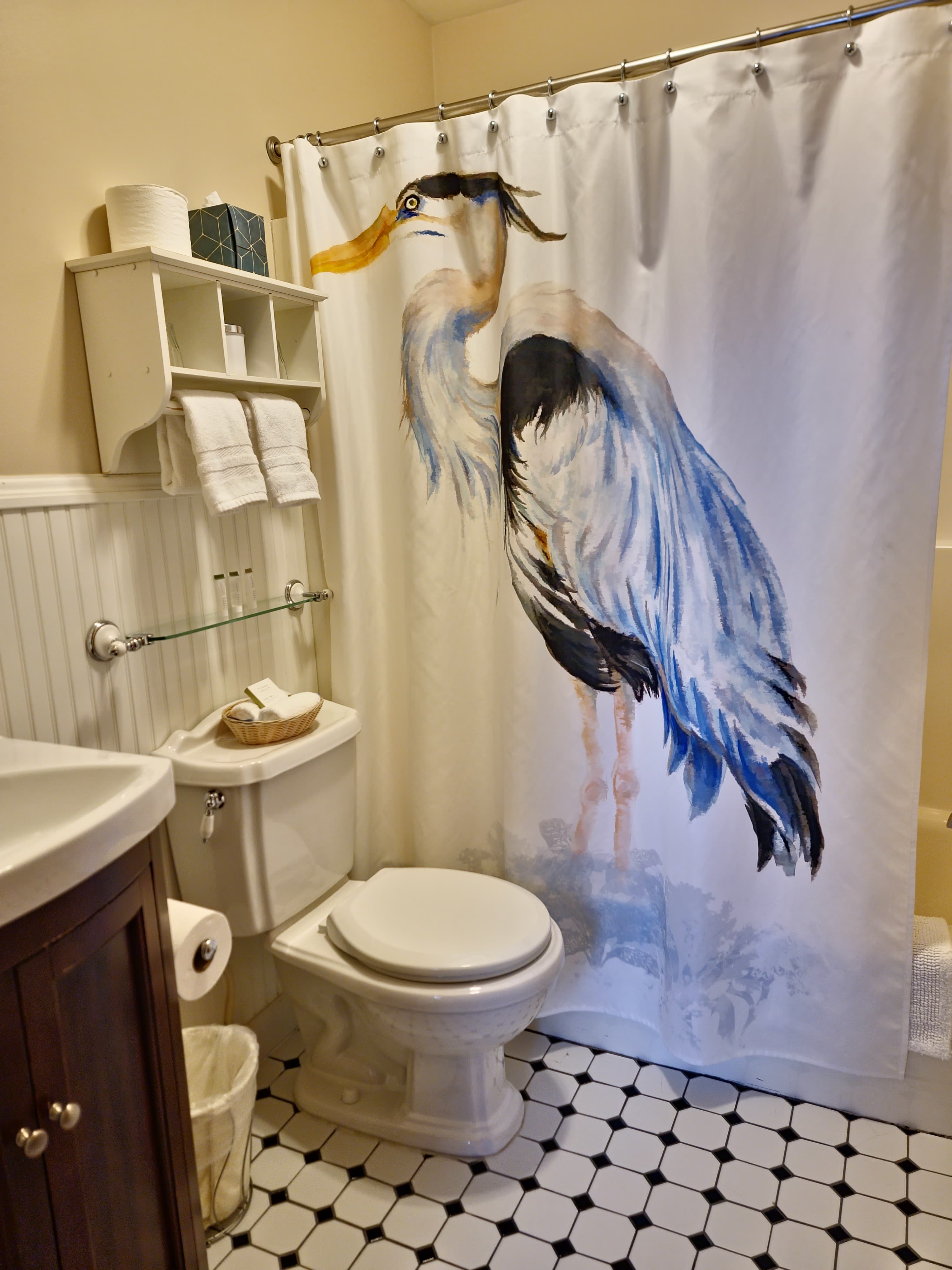 A bathroom featuring a decorative shower curtain with a painted heron design.