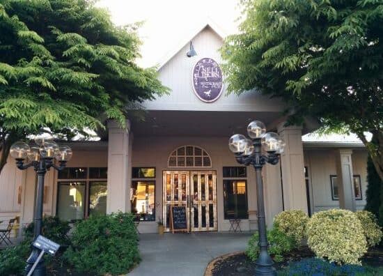 Front view of a building with large windows and decorative street lamps, surrounded by greenery.