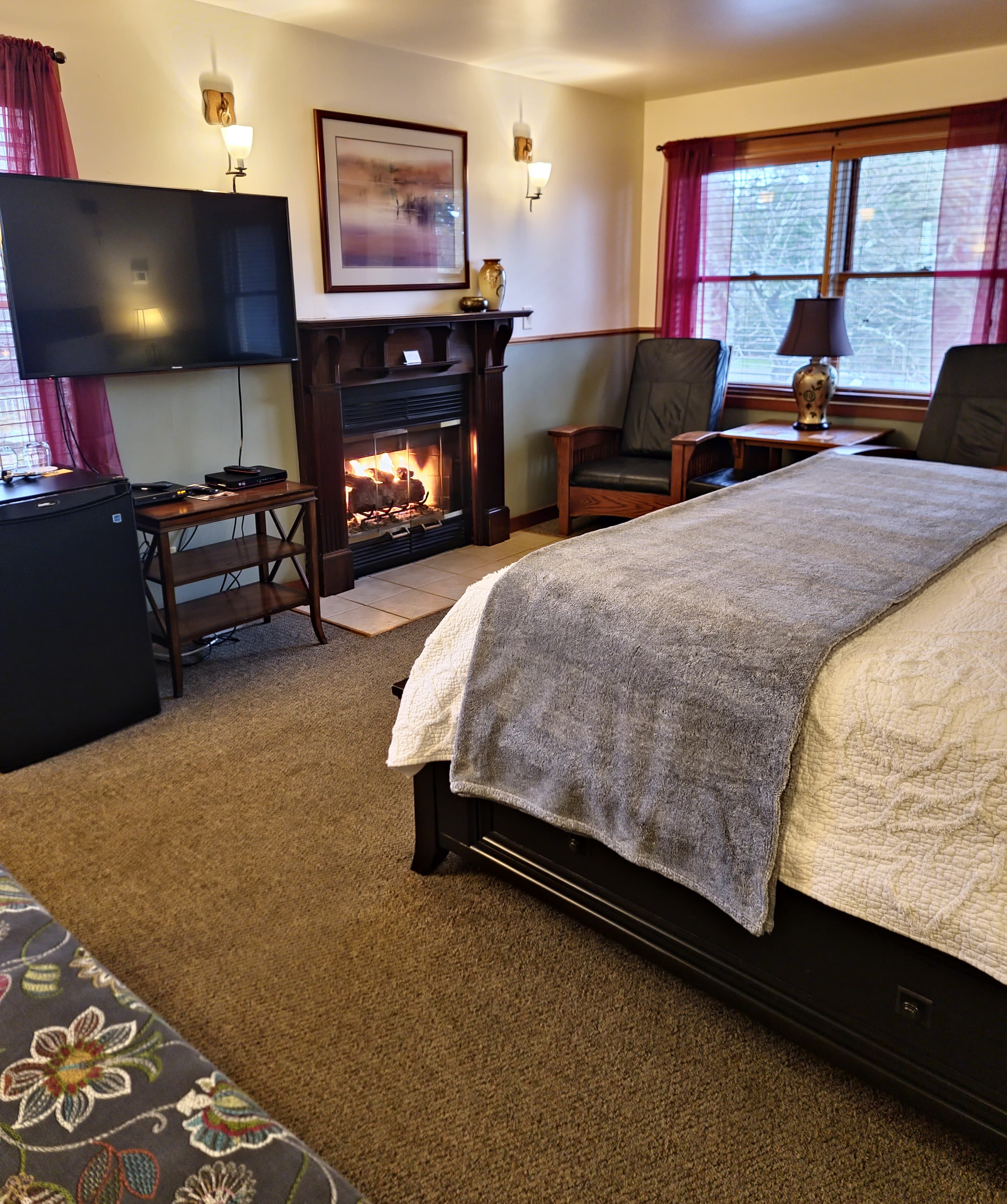 Cozy hotel room featuring a bed, fireplace, seating area, and a television.