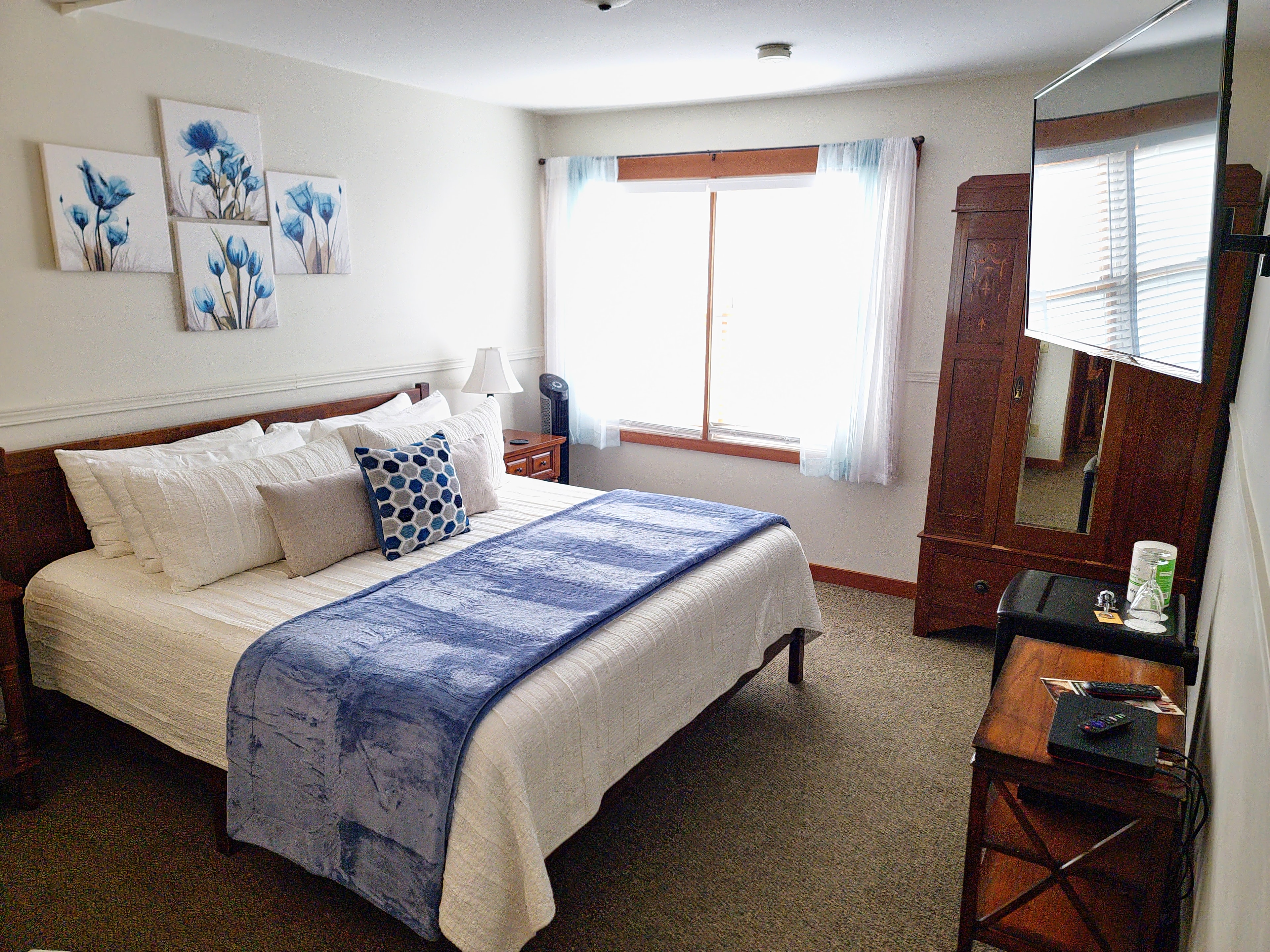 Cozy bedroom with a double bed, blue accents, and warm natural light from a window.